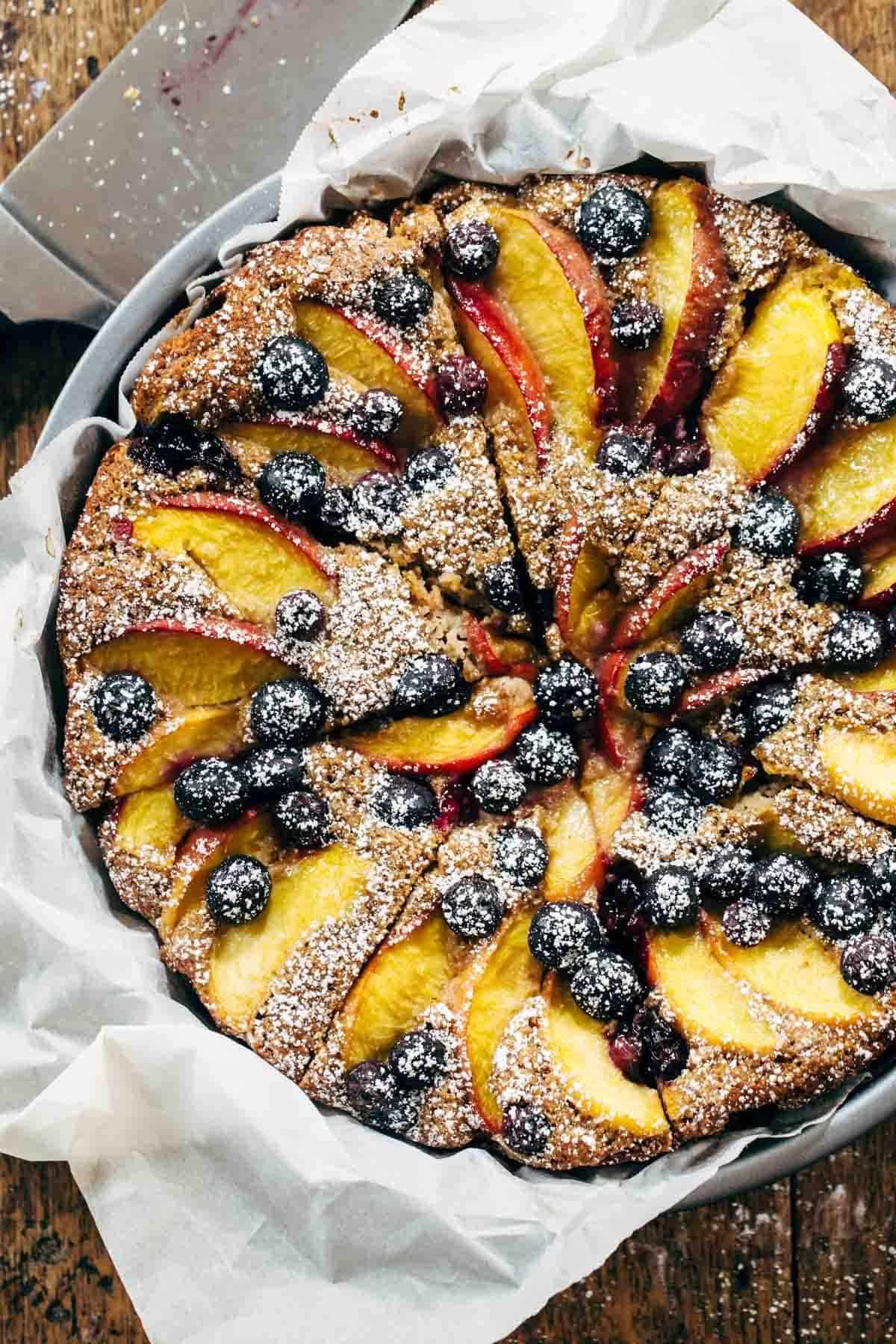 Blueberry Peach Cake recipe uses simple ingredients, whole wheat, no refined sugar, and has a STUNNING presentation. YUM! | pinchofyum.com A dessert baked with fruit and powdered sugar on top.
