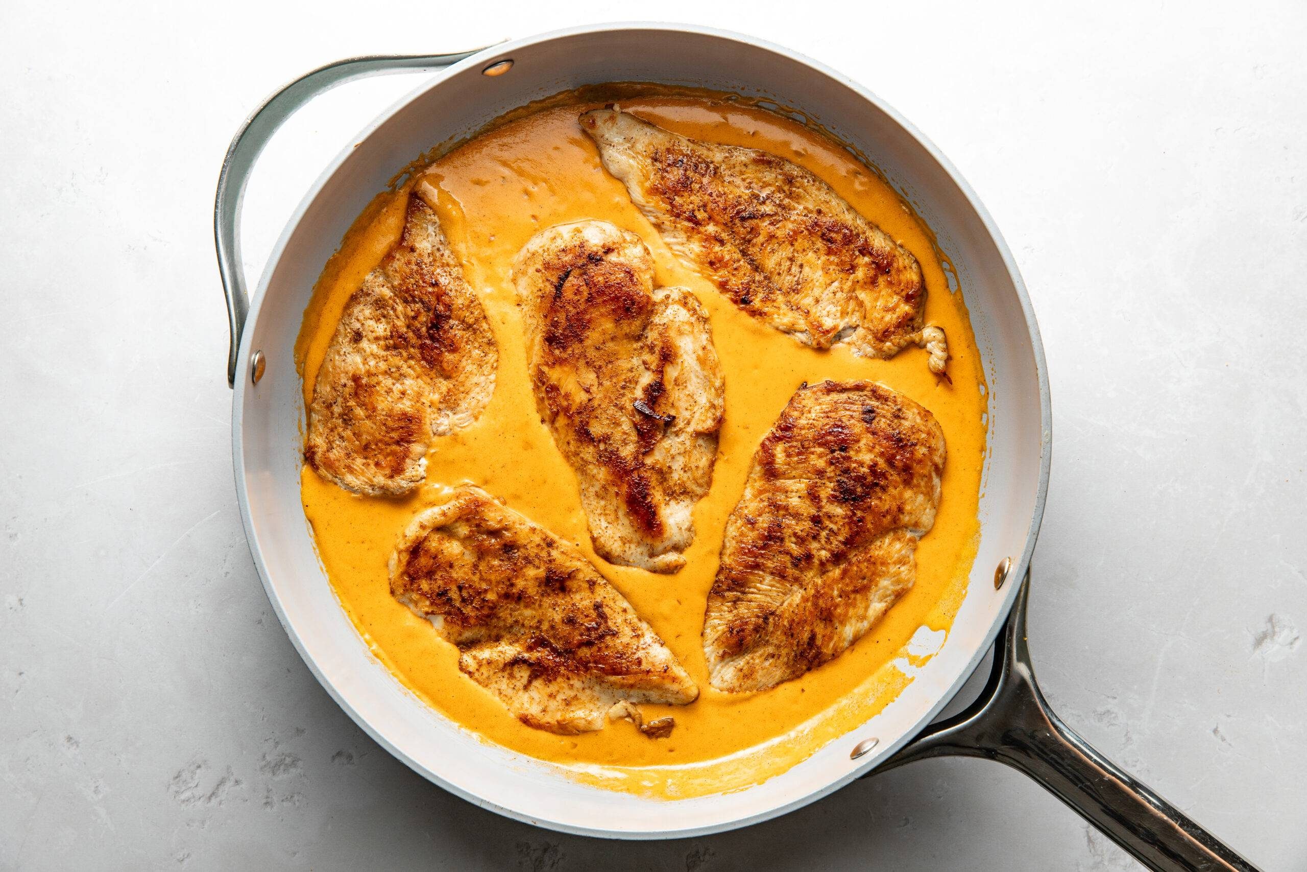 Chicken in creamy cajun sauce in a skillet.