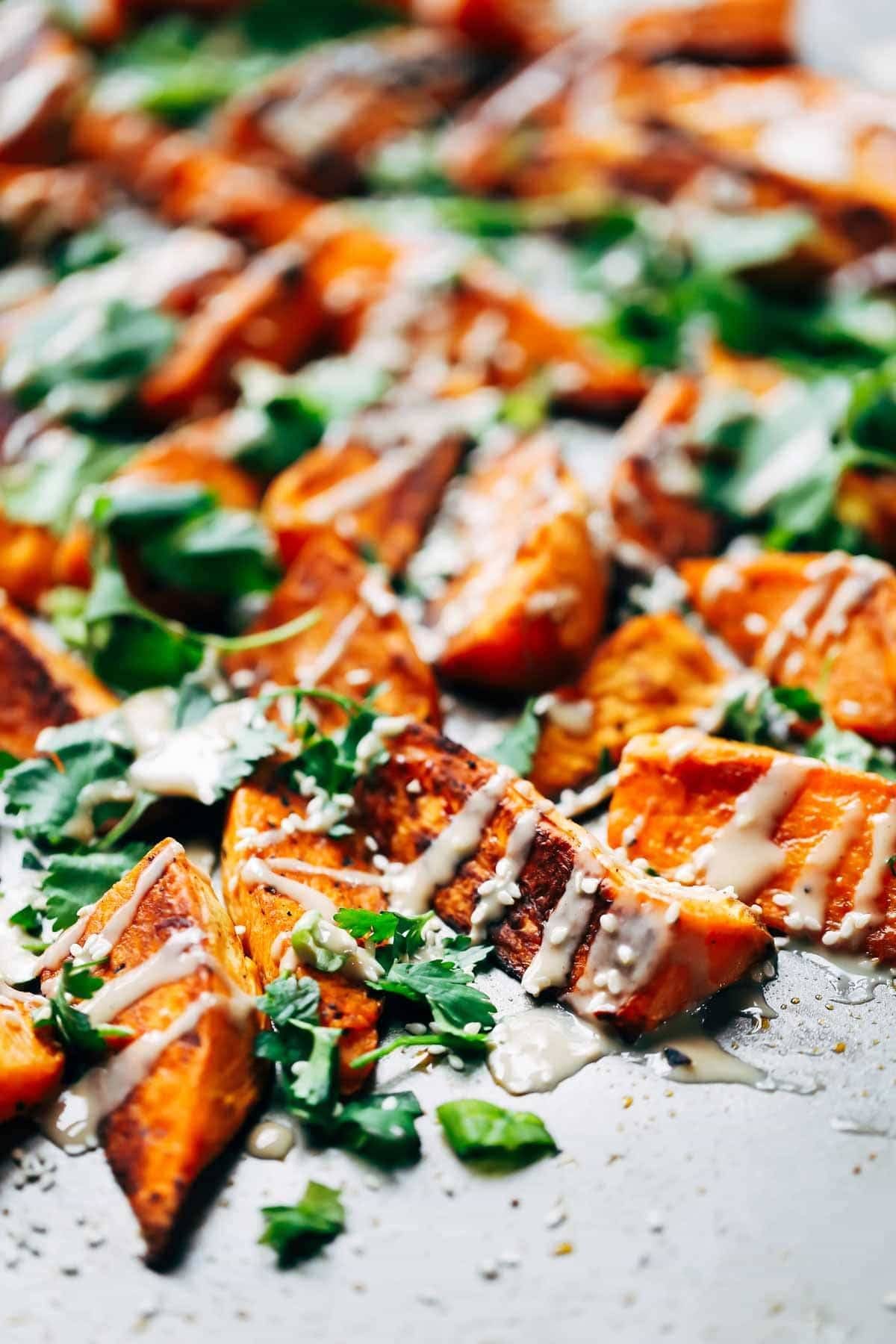 Roasted Sweet Potatoes topped with tahini, sesame oil, cilantro, and sesame seeds.