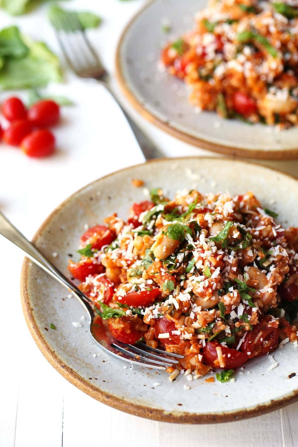Asiago White Beans with Farro, Kale, and Tomatoes on a plate with a fork.