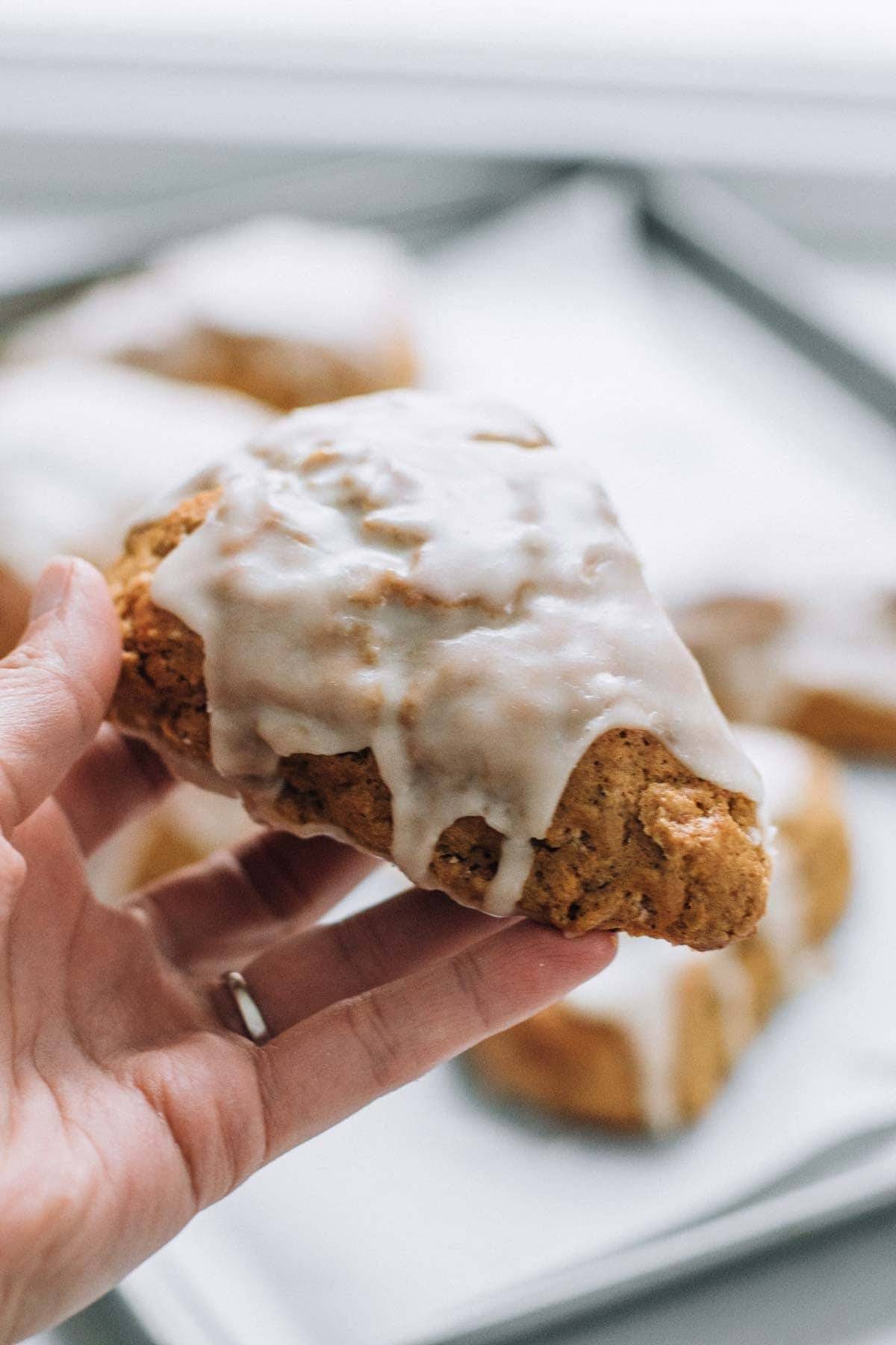 Hand holding a scone with glaze.