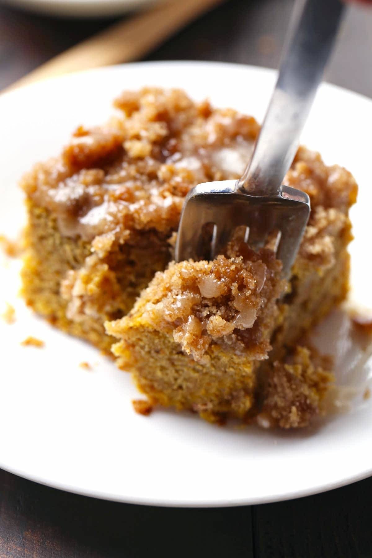 Cinnamon Streusel Pumpkin Coffee Cake with Maple Glaze on a white plate with a fork.